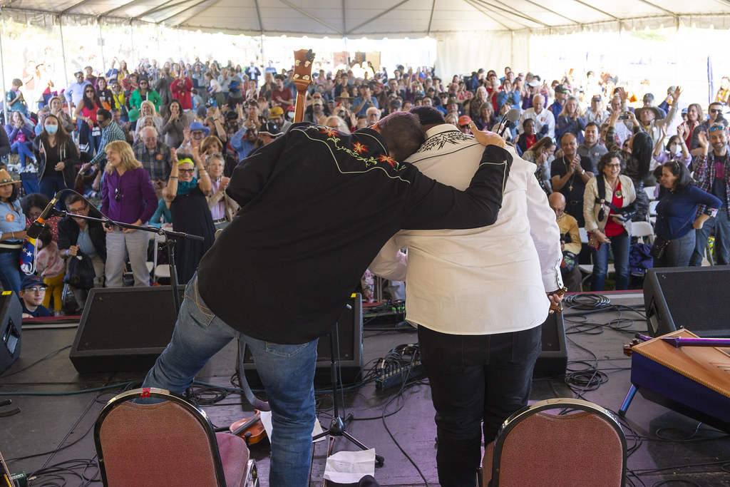 Pictured from behind, Joe Troop has his arm around Larry Bellorin following their performance at the 2022 Richmond Folk Festival.