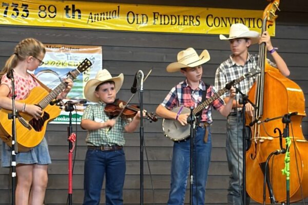 4 kids play instruments at the 2025 Galax Old Fiddlers Convention