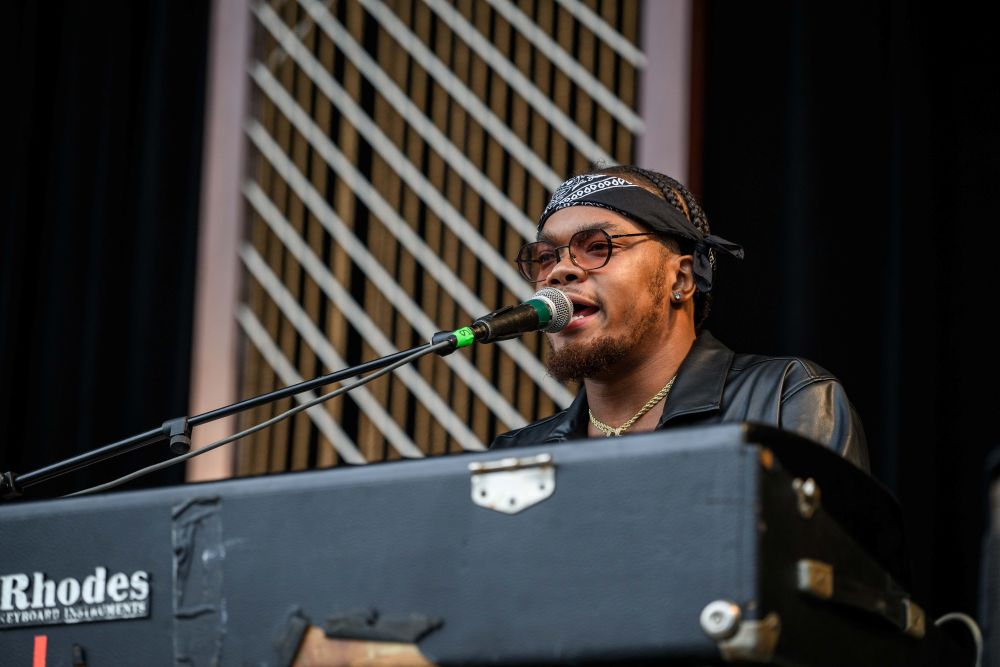 A man sits at a keyboard while singing into a microphone.