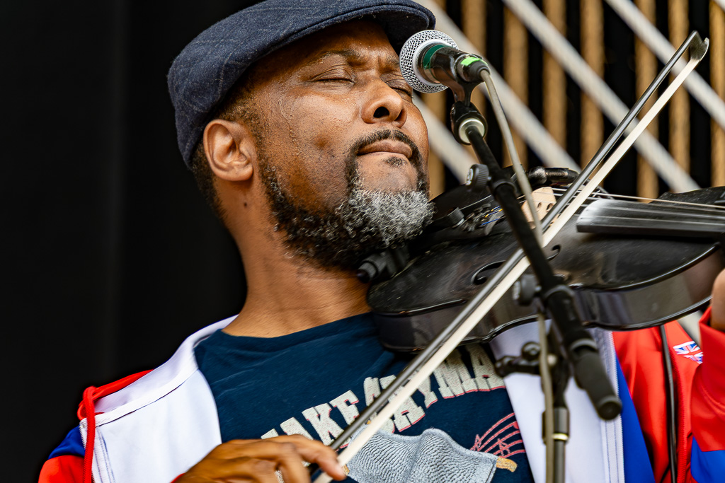A closeup of a photo of a man playing the fiddle in front of a mircorphone